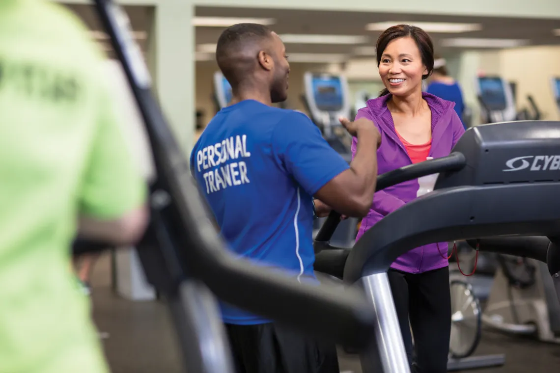 Personal trainer talking to exercising woman in exercise room